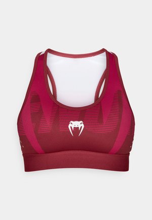 Reggiseno sportivo color marrone scuro con logo bianco e design a strati. Presenta schiena in mesh, texture a contrasto e motivo a strisce orizzontali.
