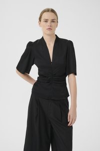 Black short-sleeve top with a deep V-neck, subtle texture, and gathered detail at the waist. Paired with wide black trousers.
