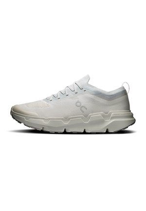 Zapatilla deportiva baja color gris claro con suela texturizada, cordones y logo "OC" en el lateral, diseñada para correr o uso casual.