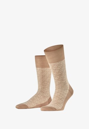 Beige Socken mit einem strukturierten Design und einem hellen Muster. Rippenbündchen oben, glatte Textur und verstärkte Zehen.