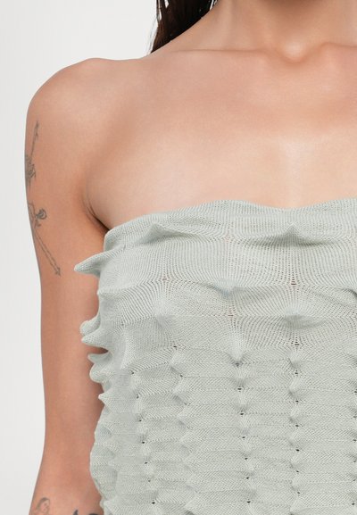 Top texturizado sin tirantes en verde claro, con un diseño en forma de ola. Fabricado en tejido de punto con patrones horizontales distintivos.