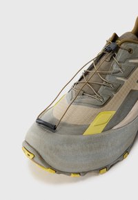 Chaussure de trail légère en gris avec des accents jaunes. Dotée d'une tige texturée, d'un bout arrondi et d'un système de laçage rapide pour un maintien sûr.