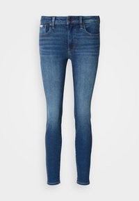Slim-fit džíny v tmavom modrom odtieni, s klasickým dizajnom piatich vreciek, pútkami na opasok a predným zapínaním na gombík. Stredné umývanie s jemným vyblednutím.