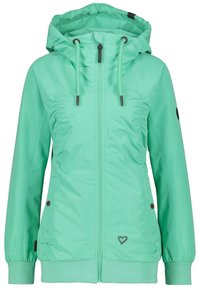 Veste zippée vert clair avec capuche, poignets élastiques et poches latérales. Présente des sections froncées et un petit logo en forme de cœur sur l'ourlet.