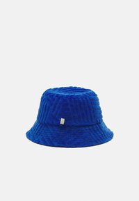 Chapeau bleu en seau en tissu texturé, présentant un motif géométrique et un petit logo en accent sur le côté. Design doux et structuré.