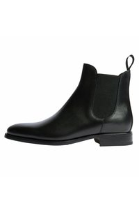 Botín Chelsea de cuero negro con paneles laterales elásticos, textura suave, punta redondeada y tacón bajo apilado. Asa en la parte trasera para ponerlo y quitarlo fácilmente.