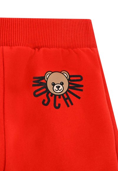 Rode joggingbroek met een zachte textuur, elastische tailleband en een grafisch ontwerp van een berengezicht met het woord "MOSCHINO" in het zwart.