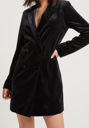 Czarna sukienka marynarkowa z aksamitu z klapami z nacięciem, dwurzędowymi guzikami, długimi rękawami i dopasowanym krojem. Gładka faktura i długość nad kolano.