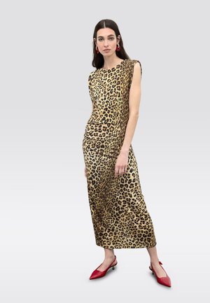 Vestido de satén con estampado de leopardo, de corte relajado, sin mangas y con detalles drapeados. Combinado con zapatos rojos de punta afilada.