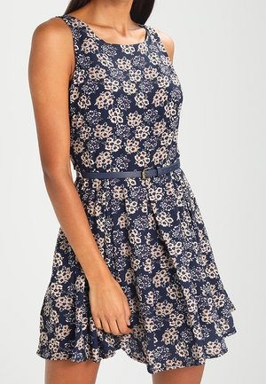 Vestido floral azul marino con un diseño sin mangas y un dobladillo con volantes. Presenta una cintura ceñida con un cinturón y un patrón de flores en tonos rosa claro y crema.