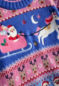 Pullover mit Santa in einem pinken Schlitten voller Geschenke, einem Einhorn, dem Mond und Sternen. Hauptsächlich blau mit pinken, roten und weißen Mustern.