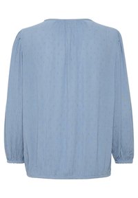 Blouse bleu clair en tissu texturé, avec un col rond, des manches longues et des poignets élastiqués avec de subtils motifs à pois.
