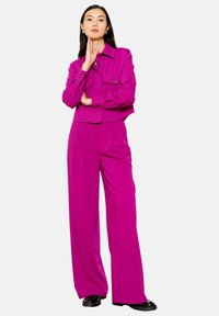 Fuchsia cropped jacket with dual pockets, paired with wide-leg trousers in the same material and color. Black shoes complete the outfit.