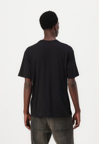 Sort bomulds T-shirt med korte ærmer, afslappet pasform og rund hals. Viser en glat tekstur og minimalistisk design, uden grafik eller logos.