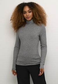 Randsydd polotröja i grått och svart, långa ärmar, figurnära design, strukturtyg, slät finish, bärs med svarta byxor.