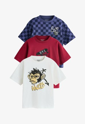 Három hajtogatott gyerekpóló: fehér majom mintával és "WILD" felirattal, piros gördeszkás és "NYC" felirattal, kék kockás "LA" felirattal.