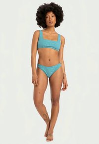 Világoskék bikini szett, texturált anyaggal, négyzet alakú nyakkivágással és állítható pántokkal a felső részen, alacsony derékú alsó résszel.