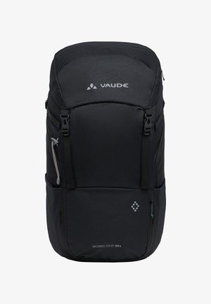 Sac à dos noir en tissu texturé, avec des bretelles ajustables, plusieurs fermetures éclair et un logo. Taille indiquée : Skomer Tour 34+.