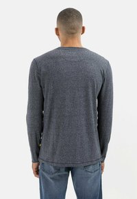 Herre langærmet skjorte i mørkegrå med en tekstureret strik. Har en rund halsudskæring og en lige kant, parret med blå jeans.