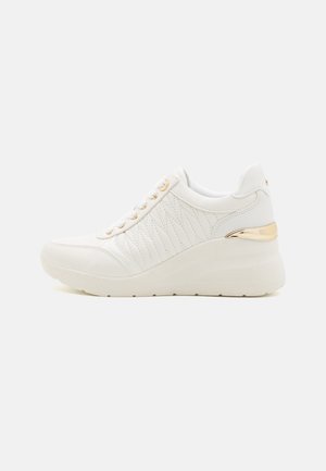 White sneaker made of leather with quilted detailing. Features a wedge heel and gold-tone accents on the heel and eyelets.