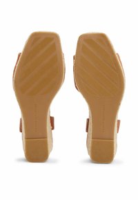 Sandales à plateforme beiges avec des détails en jute tressé, semelle extérieure en caoutchouc et brides latérales autour de la cheville. Le dessous présente un profil texturé pour une meilleure adhérence.