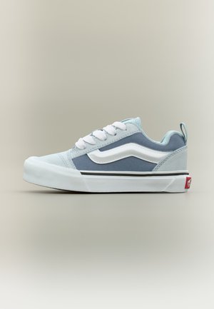 Világoskék és fehér alacsony szárú sportcipő fehér fűzővel, fehér oldalsávval és vastag fehér talppal, semleges háttéren.