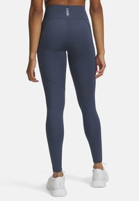 Leggings blu navy realizzati in tessuto elasticizzato con vita alta; presentano dettagli perforati sulla parte inferiore delle gambe e una texture liscia.