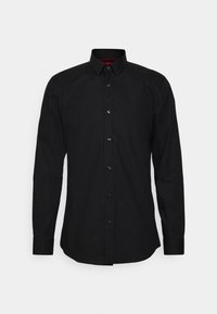 Camisa negra de manga larga con botones en la parte frontal, cuello clásico, hecha de tela suave. Cuenta con botones negros y un detalle rojo en el interior del cuello.