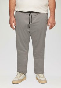 Lichtgrijze chino's met een rechte snit, elastische trekkoord tailleband en zijzakken. Gestyled met beige sneakers met textuurelementen.