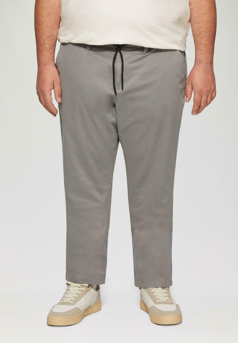 Lichtgrijze chino's met een rechte snit, elastische trekkoord tailleband en zijzakken. Gestyled met beige sneakers met textuurelementen.
