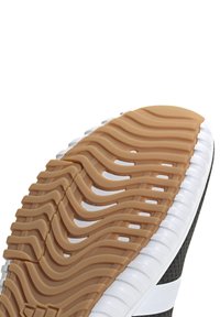 Gummisko med texturerade spår och vågiga mönster, i en beige färg med vita accenter längs kanterna.