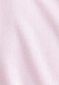 Gros plan d'un tissu rose clair avec une surface lisse, légèrement texturée et des plis subtils.