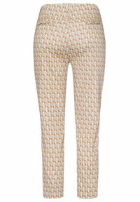 Pantalons capri ajustés présentant un fond blanc avec un motif géométrique orange et gris, une texture lisse et une taille élastique.
