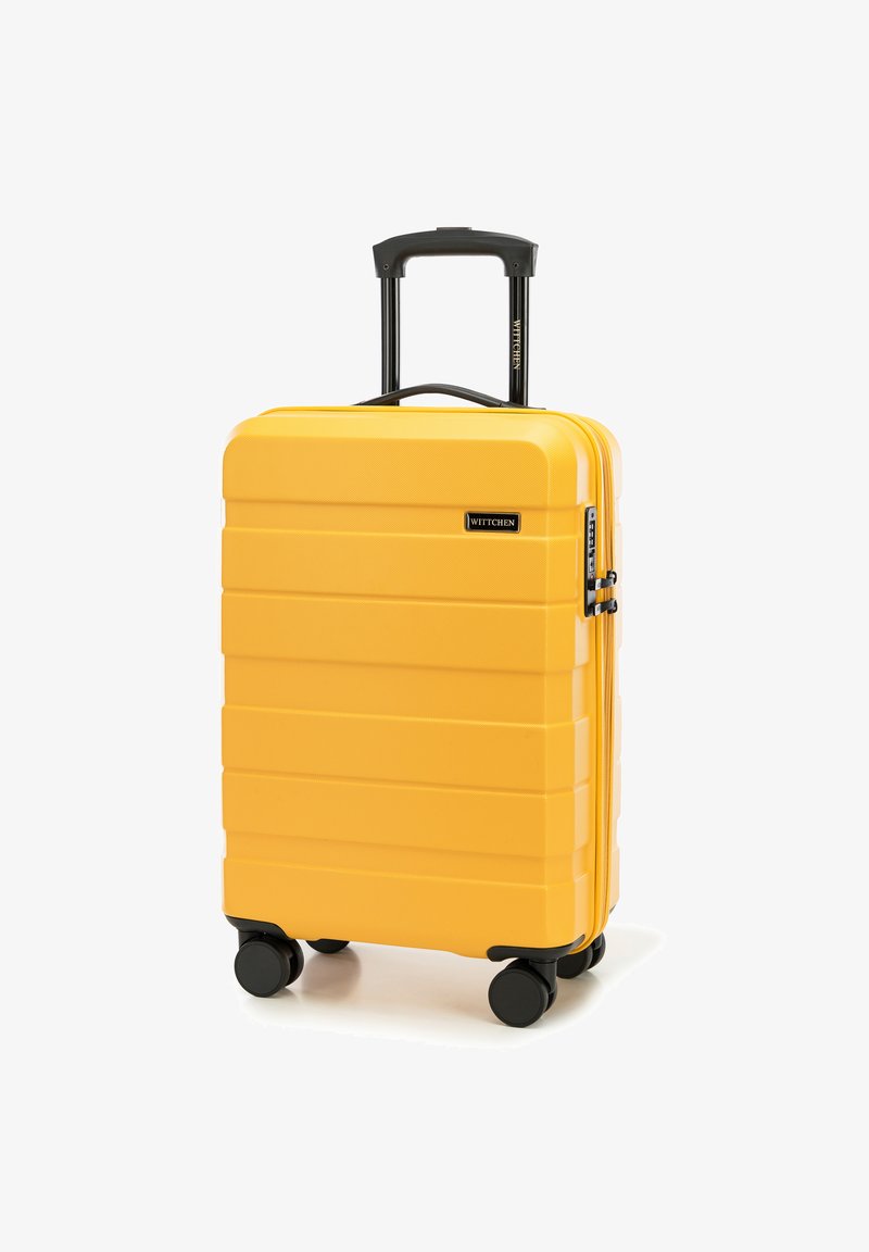 Valise jaune à coque rigide avec surface texturée, rayures verticales, poignée noire rétractable et quatre roues noires pour la mobilité.