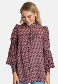 Blusa de manga larga con cuello alto y volantes; patrón floral morado en tejido ligero; mangas abullonadas con detalles fruncidos.
