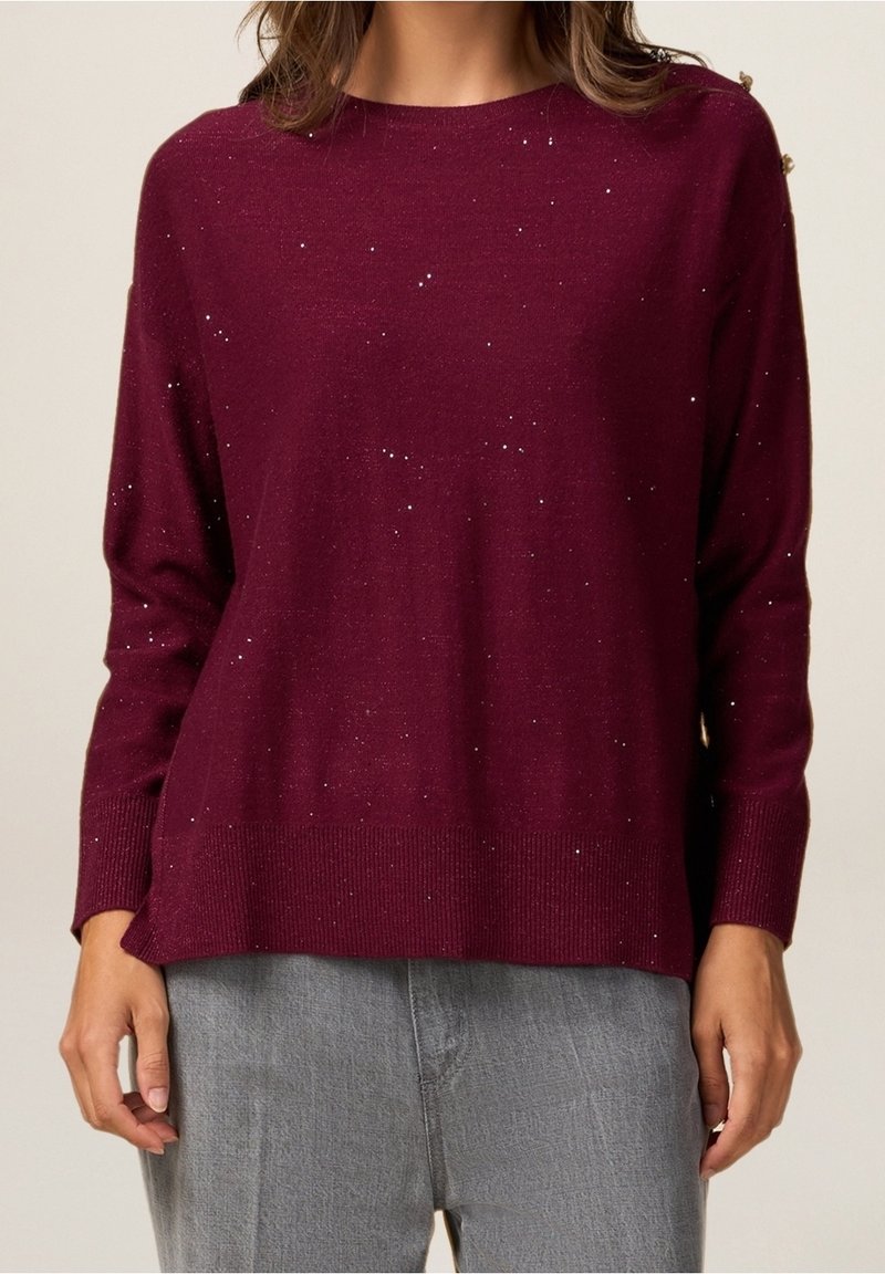 Pull bordeaux en tissu maille douce, avec une coupe décontractée, des poignets côtelés et une subtile touche de paillettes sur toute la surface.