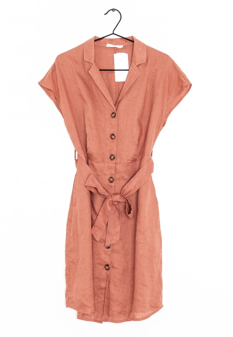 Robe en lin couleur rouille à manches courtes, fermeture à boutons sur le devant et ceinture nouée à la taille. Présente un col et des boutons en bois.