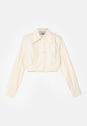 Chemise à manches longues coupée, de couleur beige clair avec des rayures verticales. Elle présente un col pointu, une fermeture par boutons et un tissu texturé.