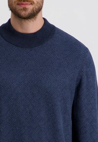 Marineblau gestrickter Pullover mit strukturiertem Muster aus erhabenen Quadraten, einem gerippten Rundhalsausschnitt und weichem Stoff.