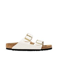 Witte slidersandalen met dubbele verstelbare bandjes, gouden gespjes, kurken binnenzool en een gestructureerd oppervlak; zwarte rubberen buitenzool.