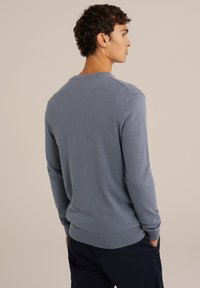 Suéter azul de manga larga hecho de un material de punto suave. Presenta un cuello redondo, dobladillo y puños acanalados, con un diseño ajustado.