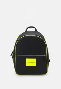 Svart Emporio Armani-ryggsäck med neongul trim, framficka med dragkedja och neongul logotyp på en vit bakgrund.