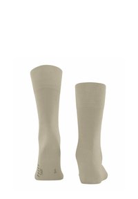 Calzini di cotone beige con un design a coste, lunghezza alla caviglia e punta rinforzata. Presentano una texture liscia e un branding minimale sulla suola.