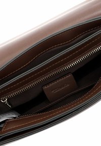Interno di una borsa a tracolla in pelle marrone con una tasca con zip e foderato con tessuto liscio, dotato di porta carte e dettagli di cucitura fine.