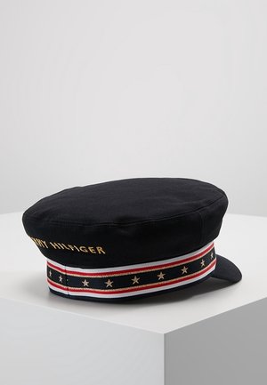 Sort sømandshat med rød, hvid og blå stribet bånd dekoreret med gyldne stjerner og "Tommy Hilfiger" broderet i guld.