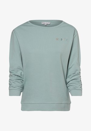 Svetr s dlouhými rukávy, světle zelené barvy, s kulatým výstřihem a nařasenými rukávy. Uprostřed se nachází nápis "GOOD VIBE" v barevném výšivce.