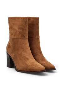 Botas de tobillo de ante marrón con punta afilada y tacón apilado, que presentan una superficie suave y un diseño minimalista.