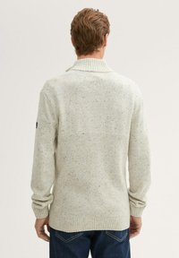 Jasnoszary sweter wykonany z dzianiny z prążkowanym kołnierzem, o fakturze ze smugami. Slim fit, długie rękawy oraz prążkowane mankiety i dół.