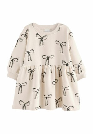 Vestido para niño pequeño de manga larga color crema con cintura fruncida y estampado de lazos dibujados a mano en negro por todo el vestido.