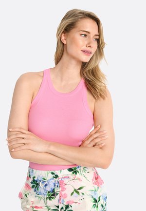 Roze geribbelde tanktop met een ronde halslijn, gecombineerd met shorts met bloemmotief met roze en blauwe bloemen op een lichte achtergrond.